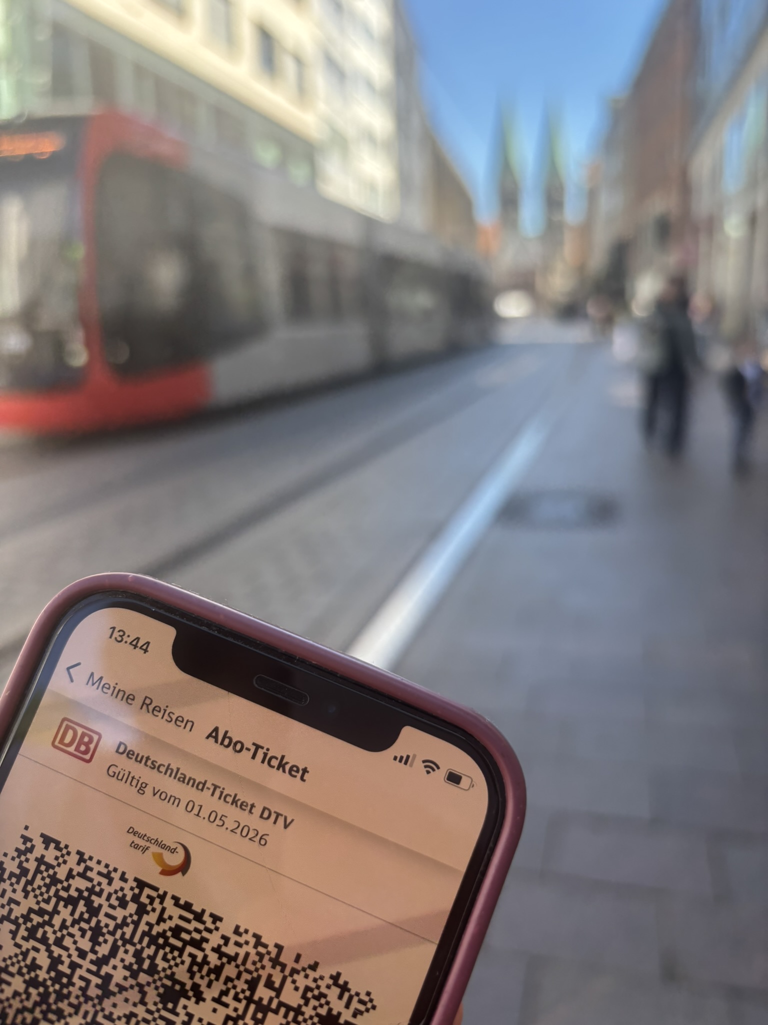Deutschland-Ticket auf einem Handy in Bremen vor einer Straßenbahn